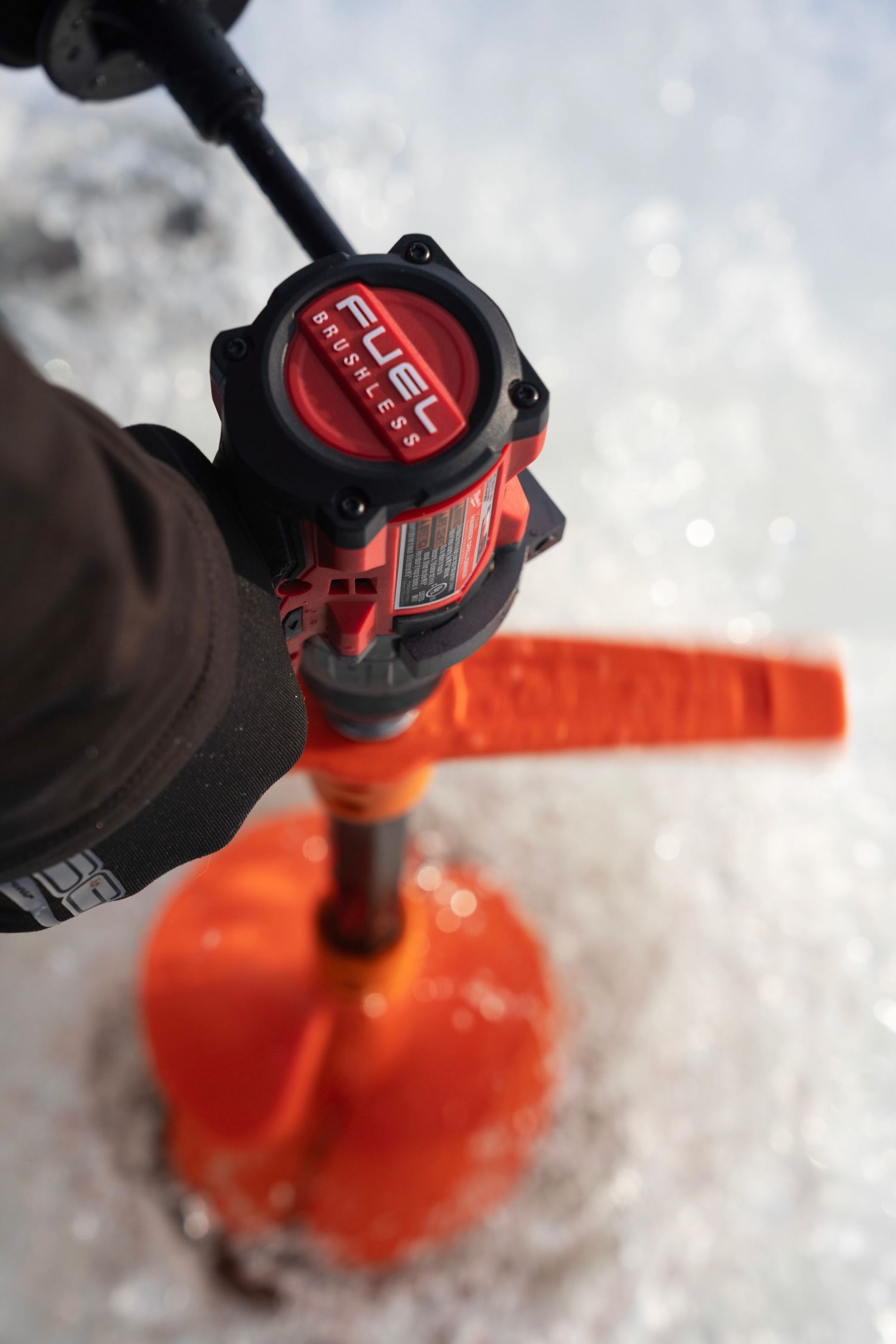 Close-up view of a Fuel powered ice auger handle with orange drill bit.