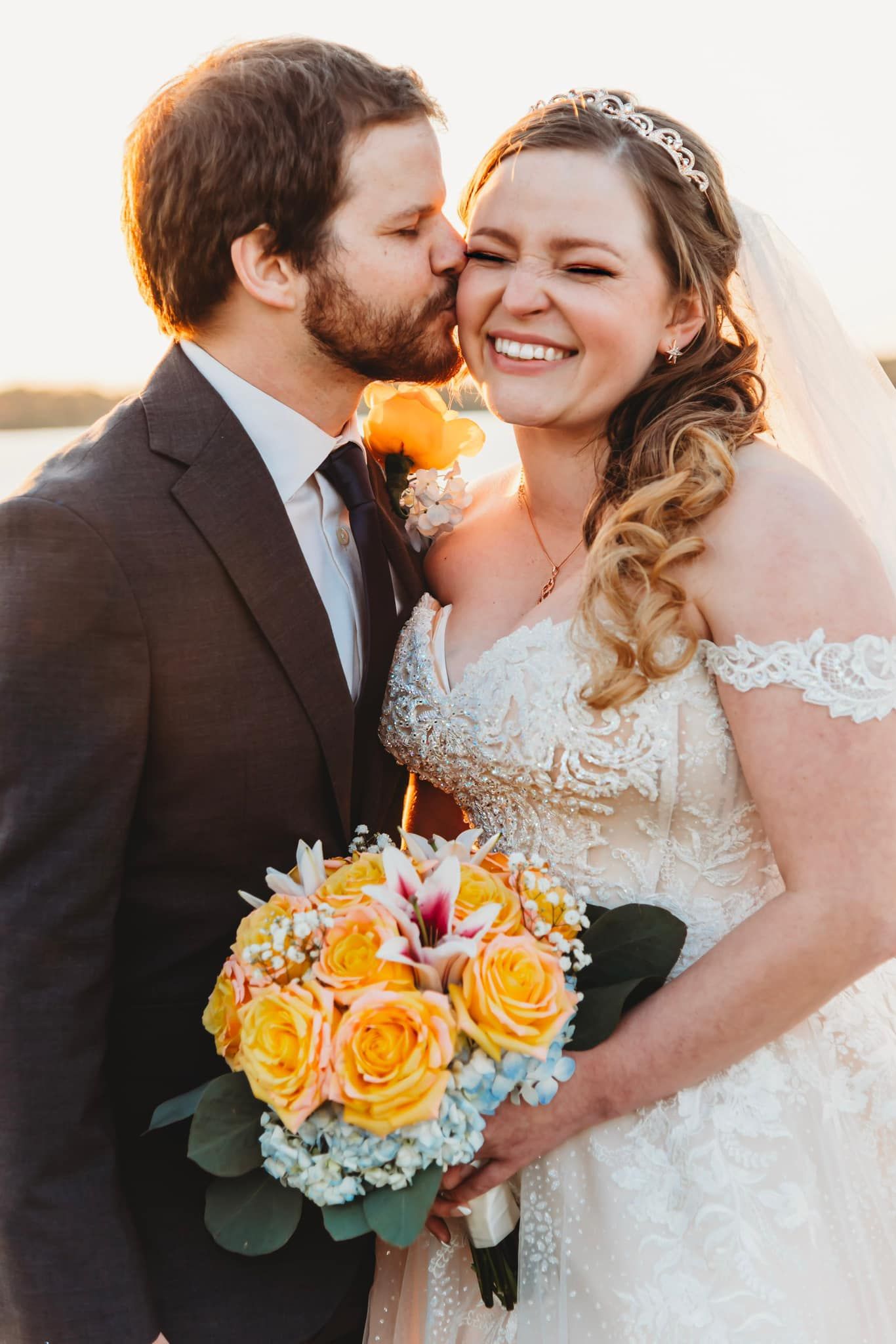 Joyful wedding moment with bouquet of yellow roses at sunset.