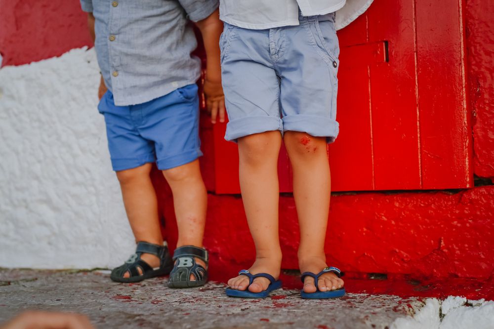 Close-up view of two pairs of legs wearing shorts standing against a red and white wall.