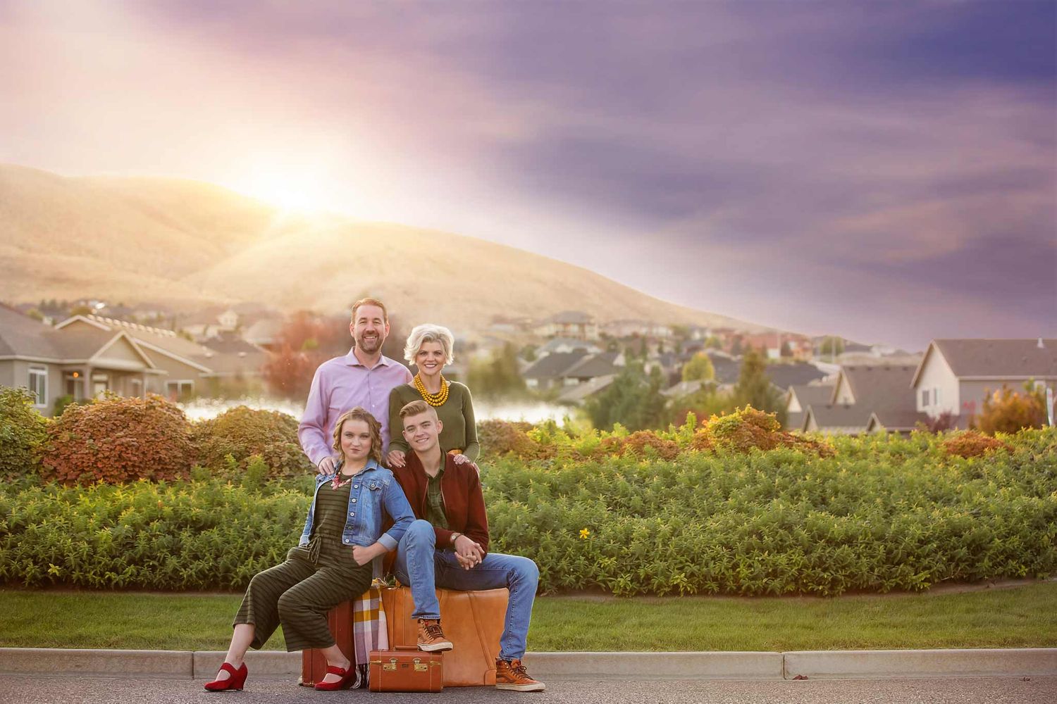 family of four sitting under a purple sunset with antique suitcases
