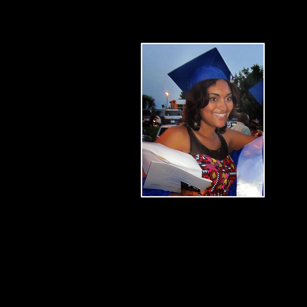 Graduate wearing blue cap and gown smiling outdoors during celebration.