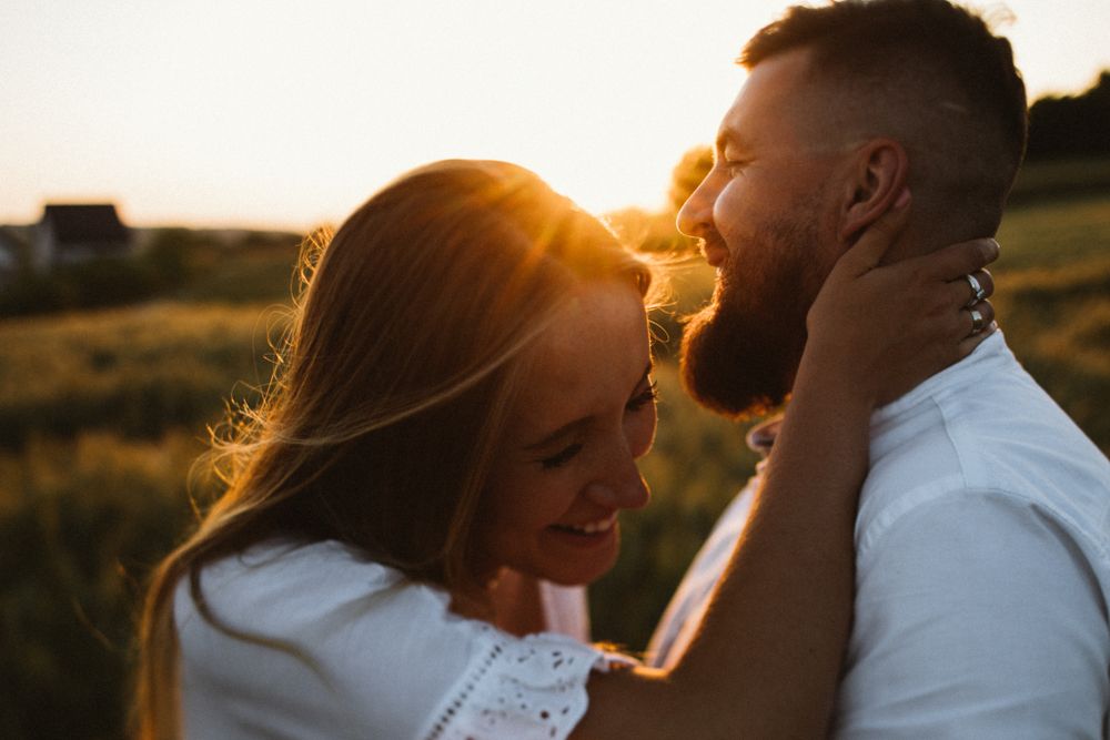 Happy couple sharing romantic moment in golden sunset light in open field.