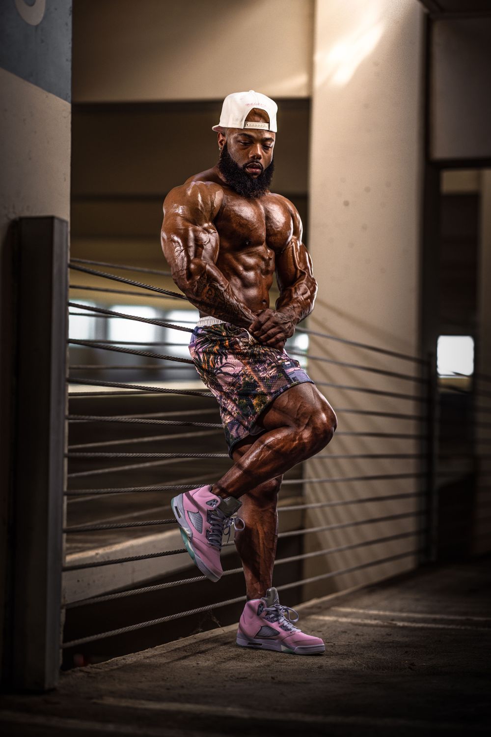Fitness model displaying sculpted physique in urban parking garage setting.