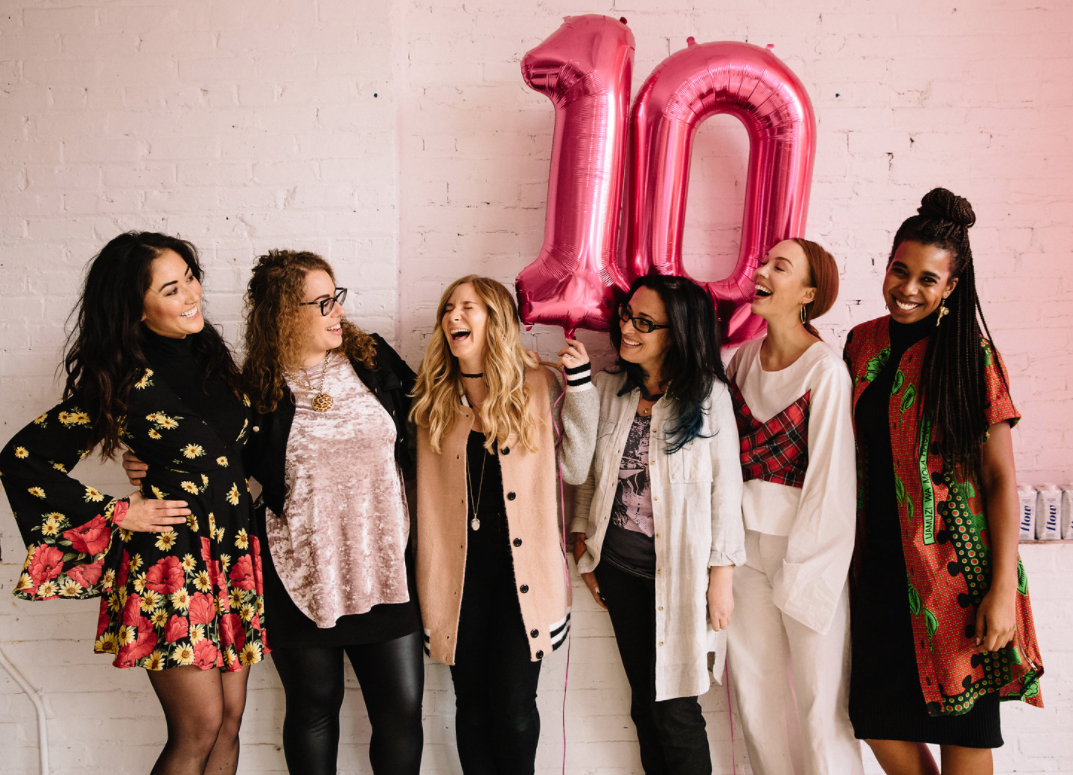 She Does the City - panel of speakers smiling and laughing in front of a pink 10 balloon