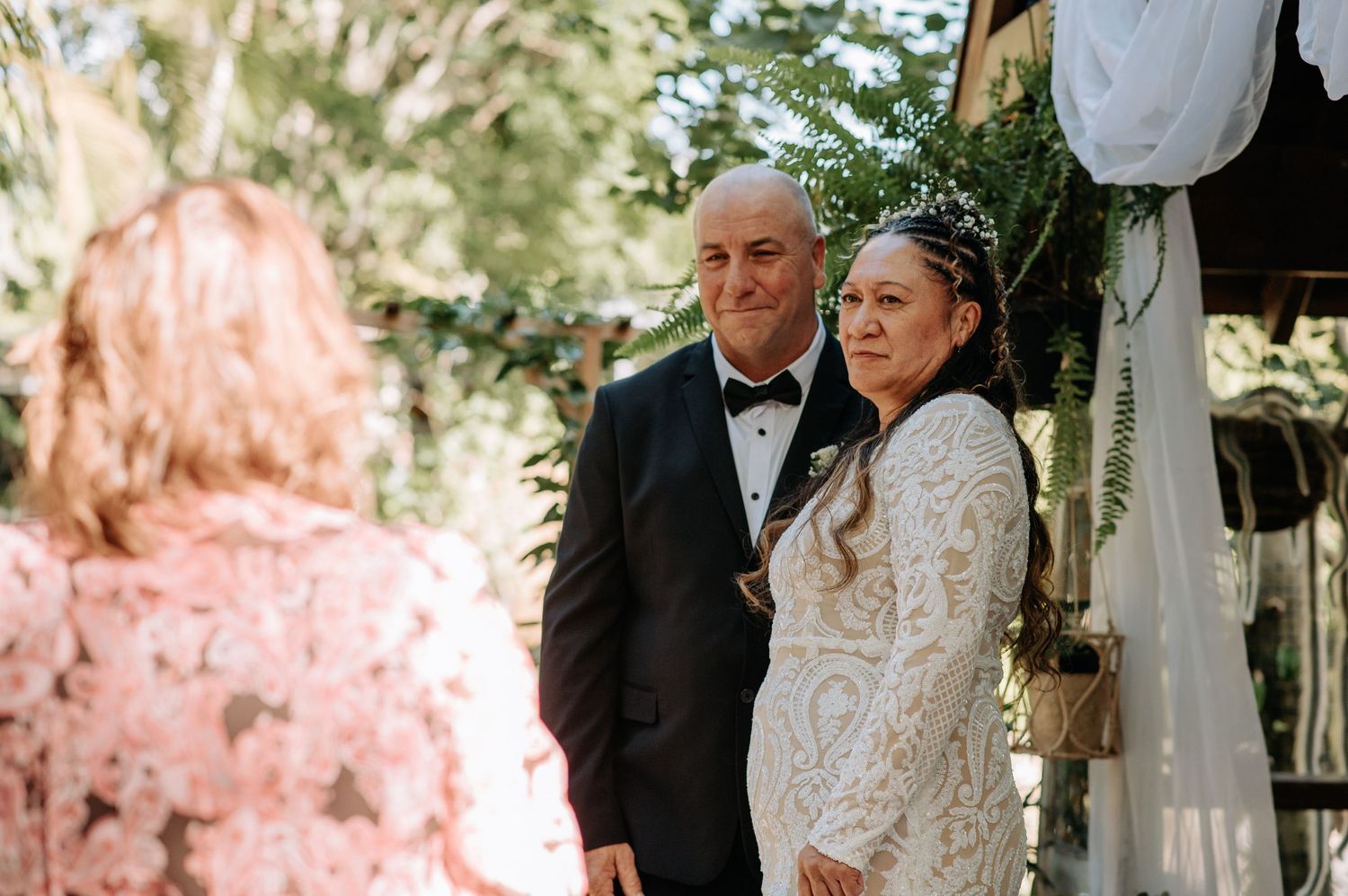 An intimate outdoor wedding ceremony with floral and fabric decorations.