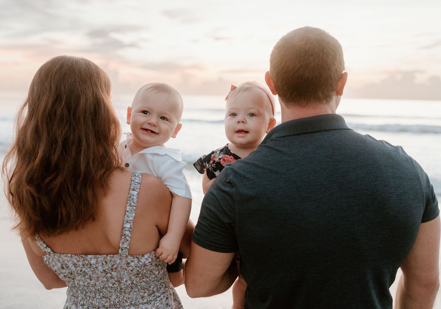 Silhouettes of family group against sunset sky at beach.