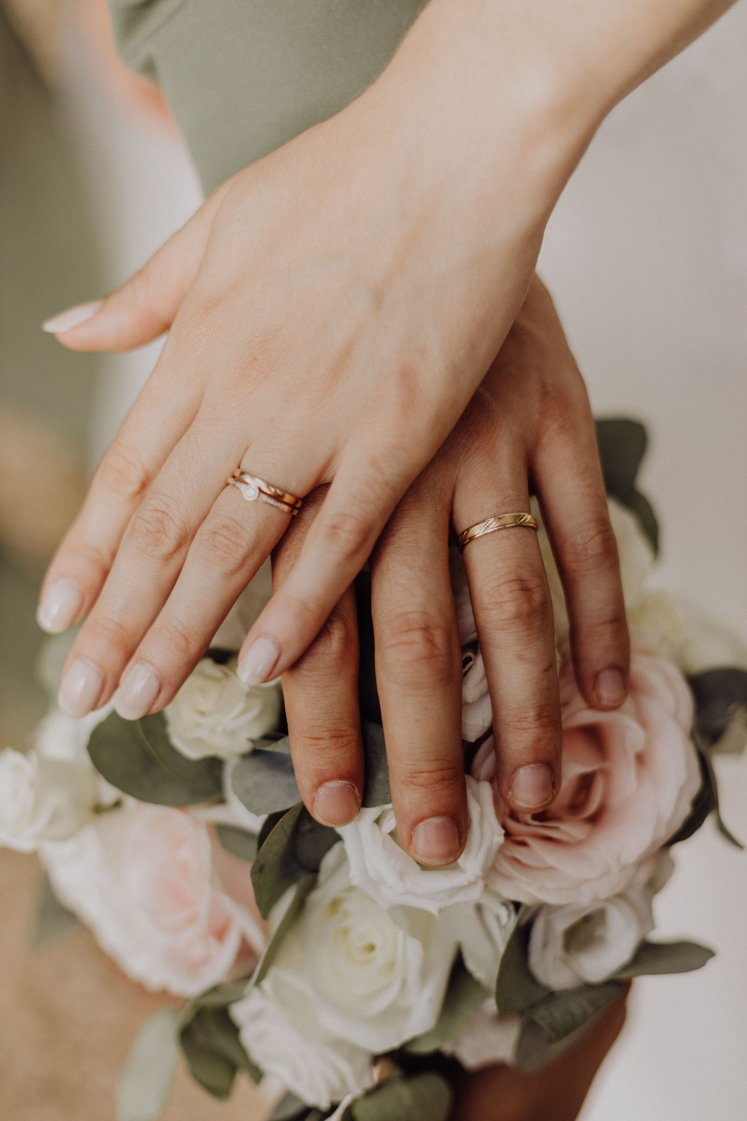 Photographe mariage Auvergne Rhône-Alpes – gros plan des alliances portées par les mariés sur un bouquet de roses blanches et roses.