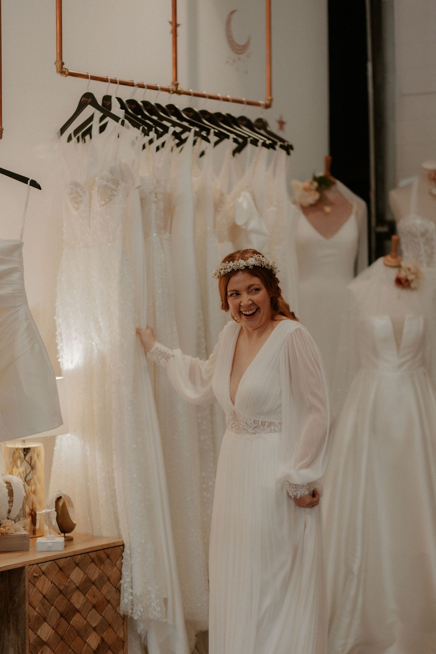 Bridal boutique interior with wedding dresses displayed on hangers and joyful moment captured.