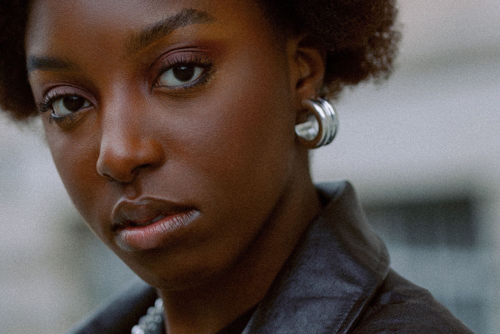 Beauty portrait featuring silver earrings and natural makeup in moody lighting.