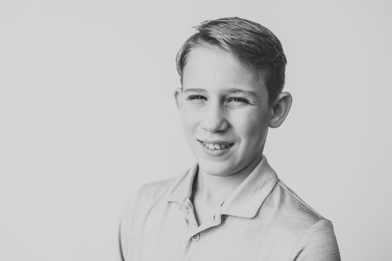 Black and white portrait in polo shirt with cheerful expression.