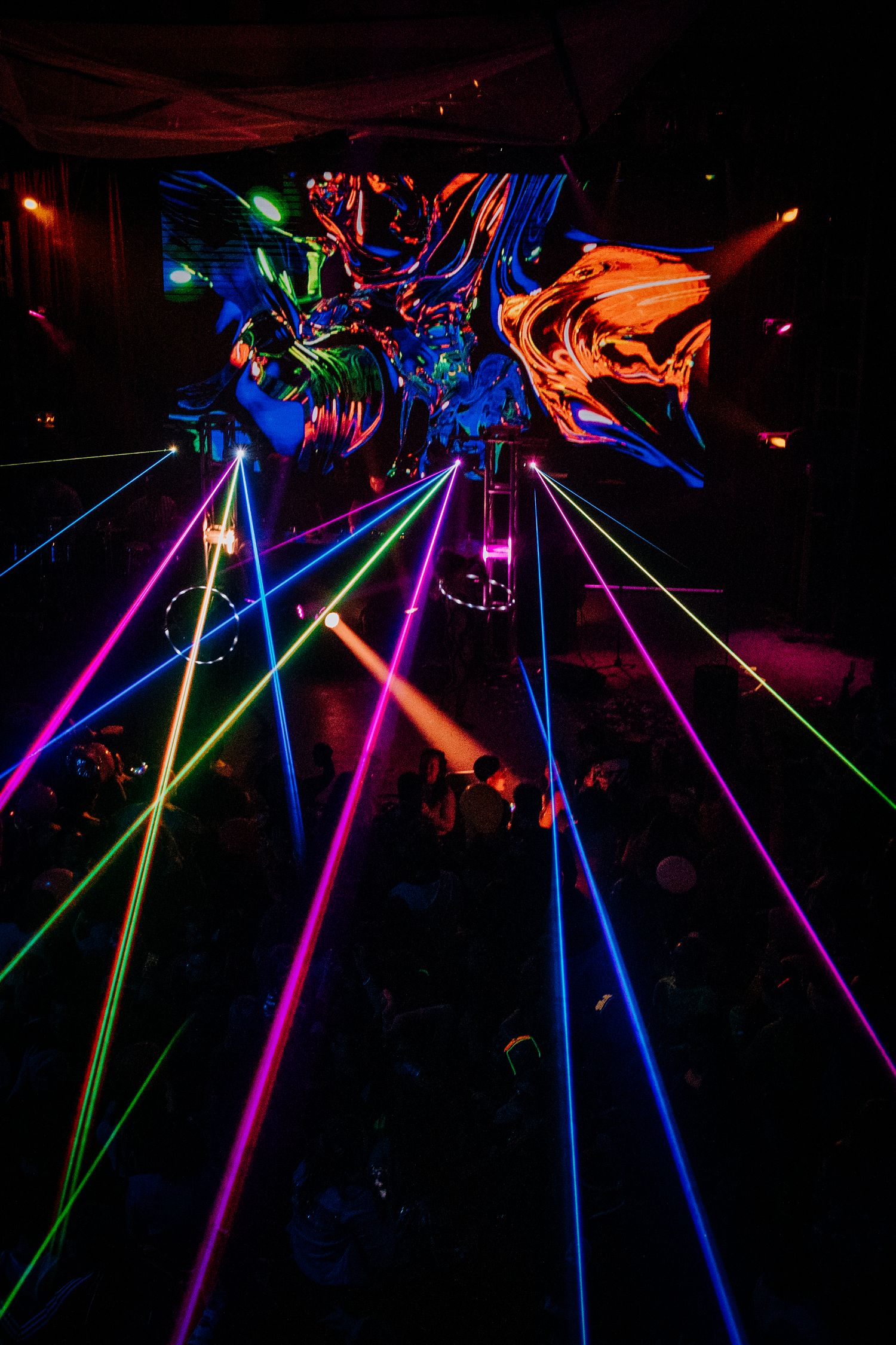 Colorful laser beams radiate from a central point creating a vibrant geometric light display.