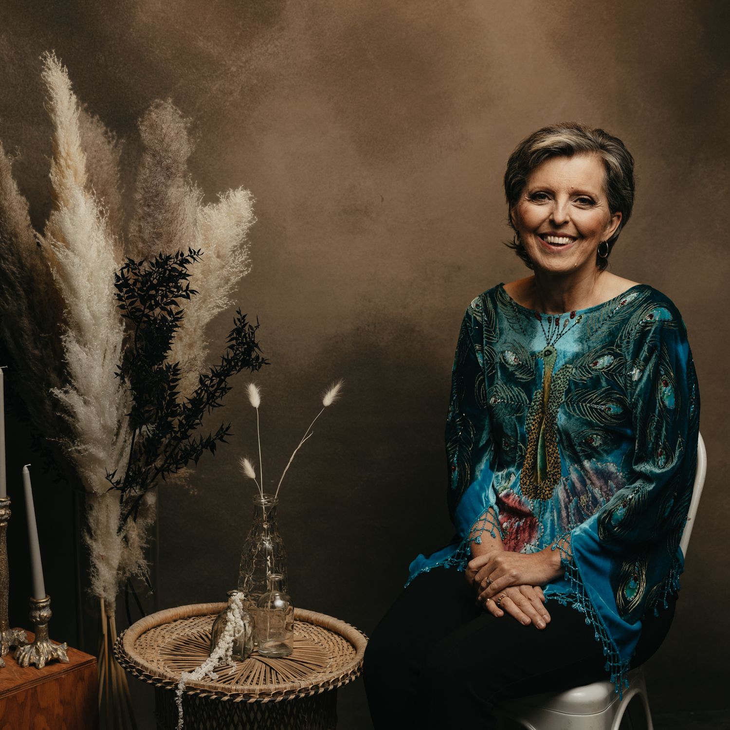 Studio portrait session featuring teal dress and decorative pampas grass arrangements.