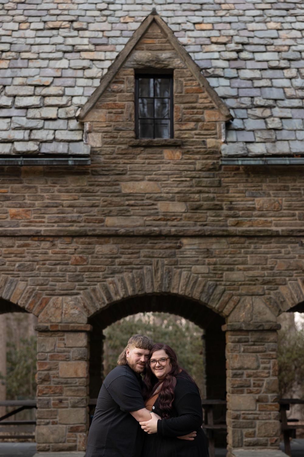A romantic moment beneath a stone archway of a historic building.