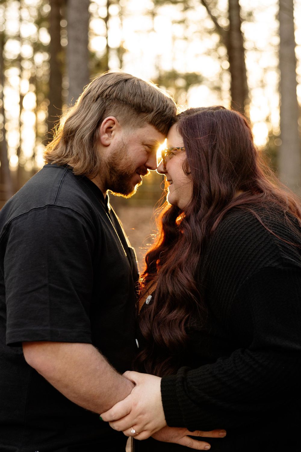 A romantic sunset moment between a couple in black attire.