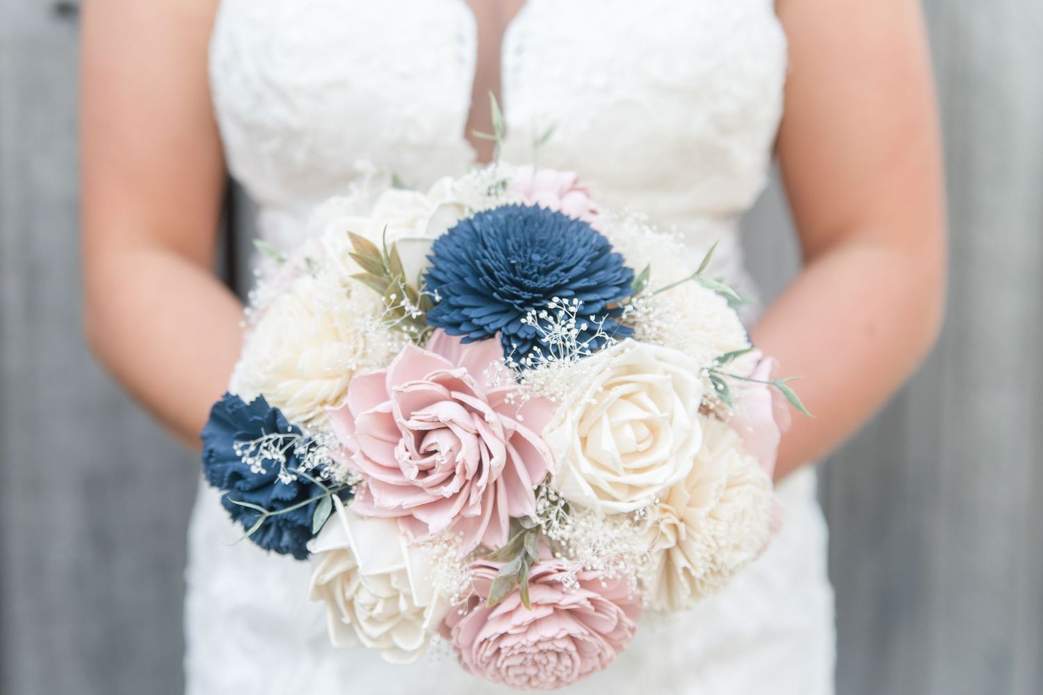 Wedding bouquet featuring blue and pink roses with white accents held against a white dress.