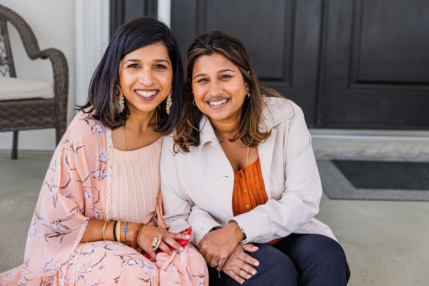 Two people sitting on porch sharing joyful smiles and laughter together.