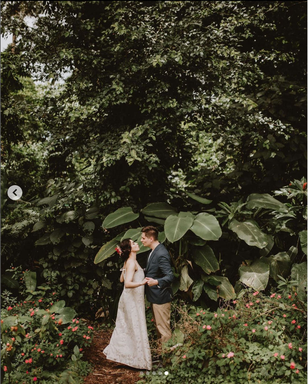 A couple embraces in a lush garden setting with tropical foliage.