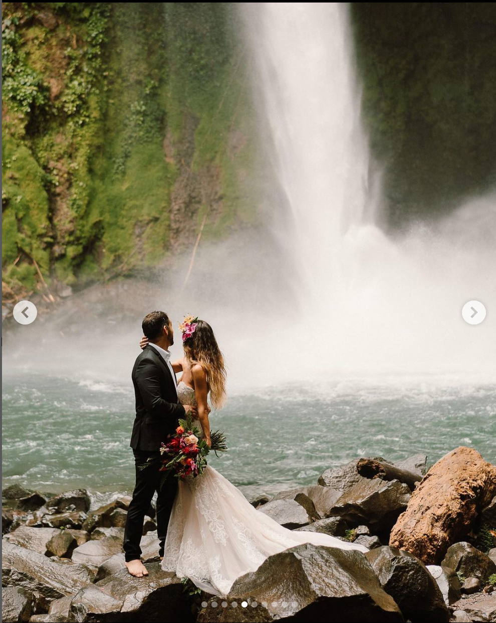 Romantic wedding portrait with waterfall and misty backdrop.