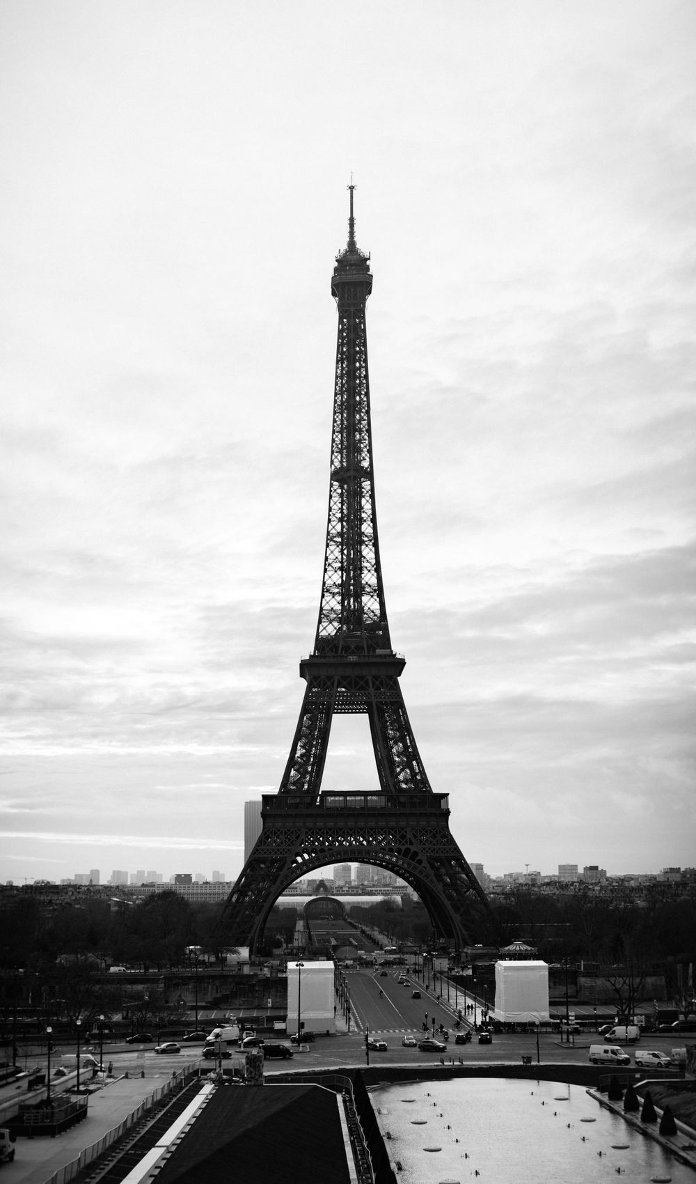 Black and white photograph of the Eiffel Tower in Paris against a cloudy sky.