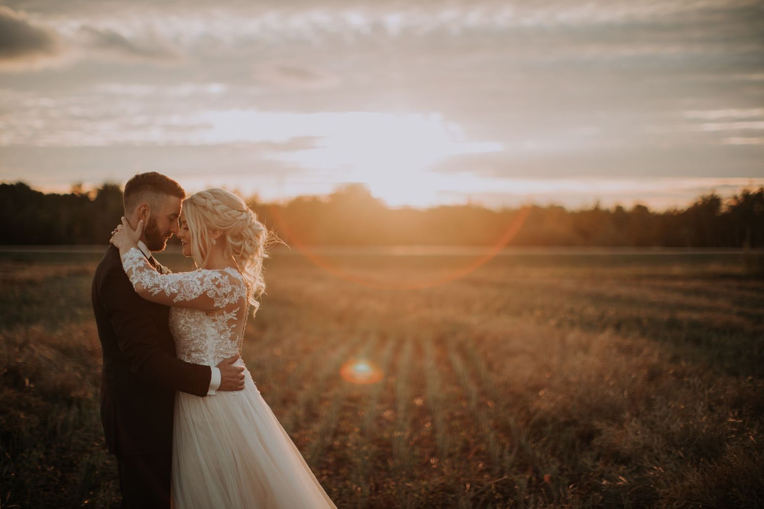 A romantic embrace in a golden field at sunset with dramatic lighting and lens flare.