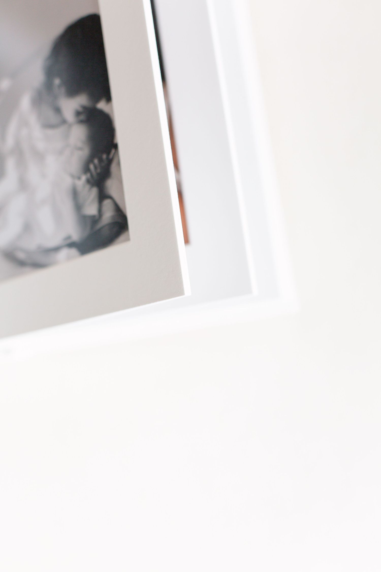 a close up view of an open matted album pages showcasing photos on a white backdrop, photo by Paula Ortiz NYC Family