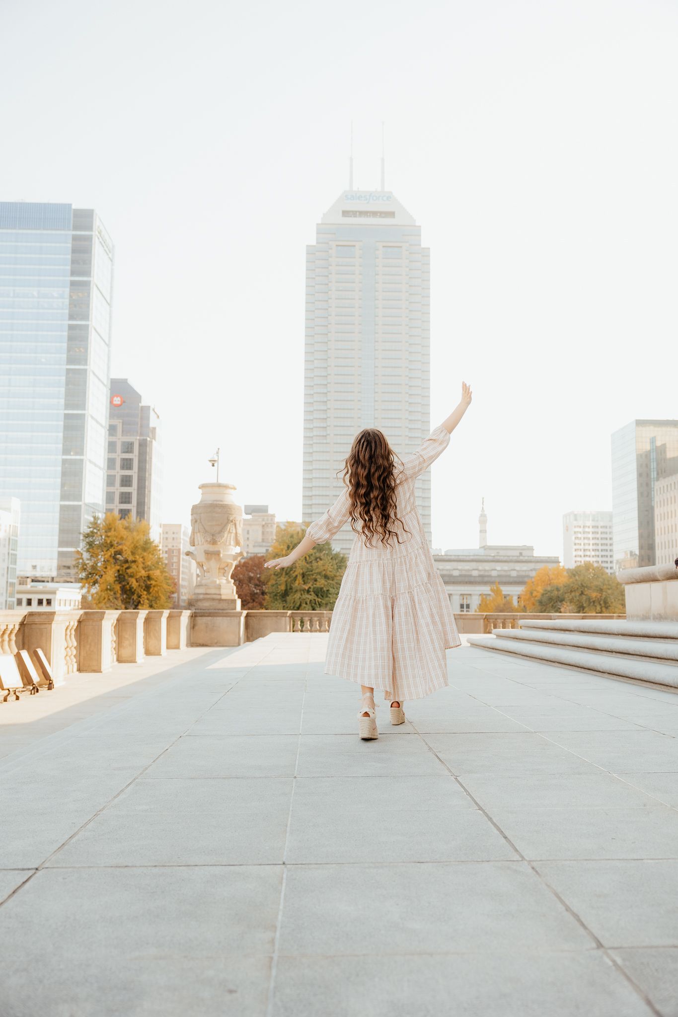 Ethereal rooftop dance scene with city buildings and autumn trees in background.
