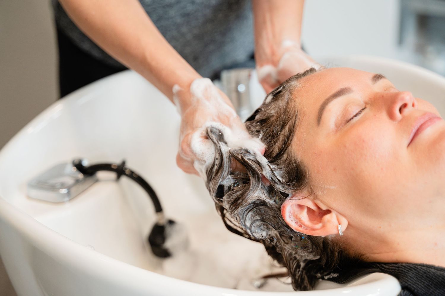 Hair washing treatment at salon sink with professional shampoo service.