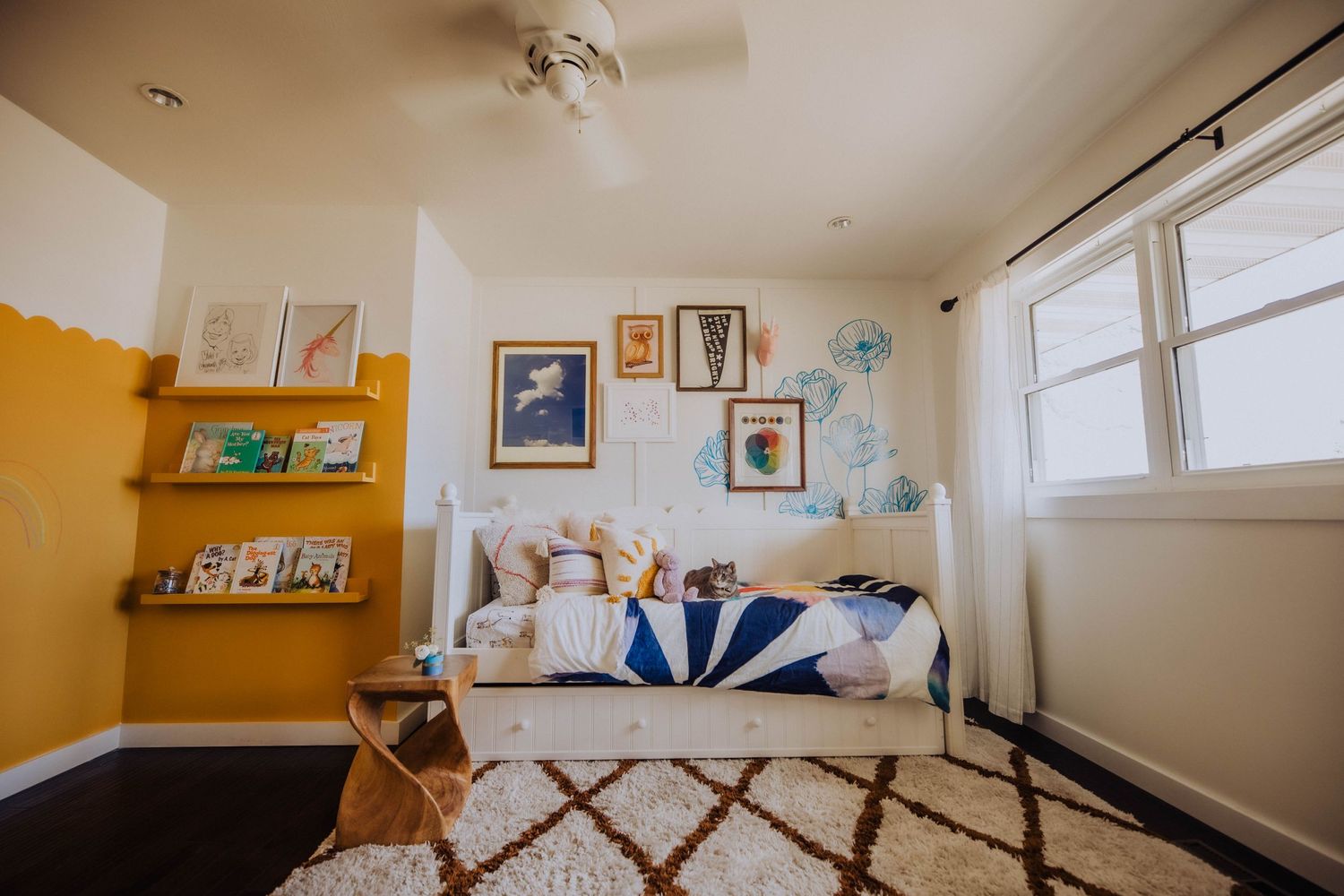 Bedroom with ceiling fan, windows, and framed artwork on walls.