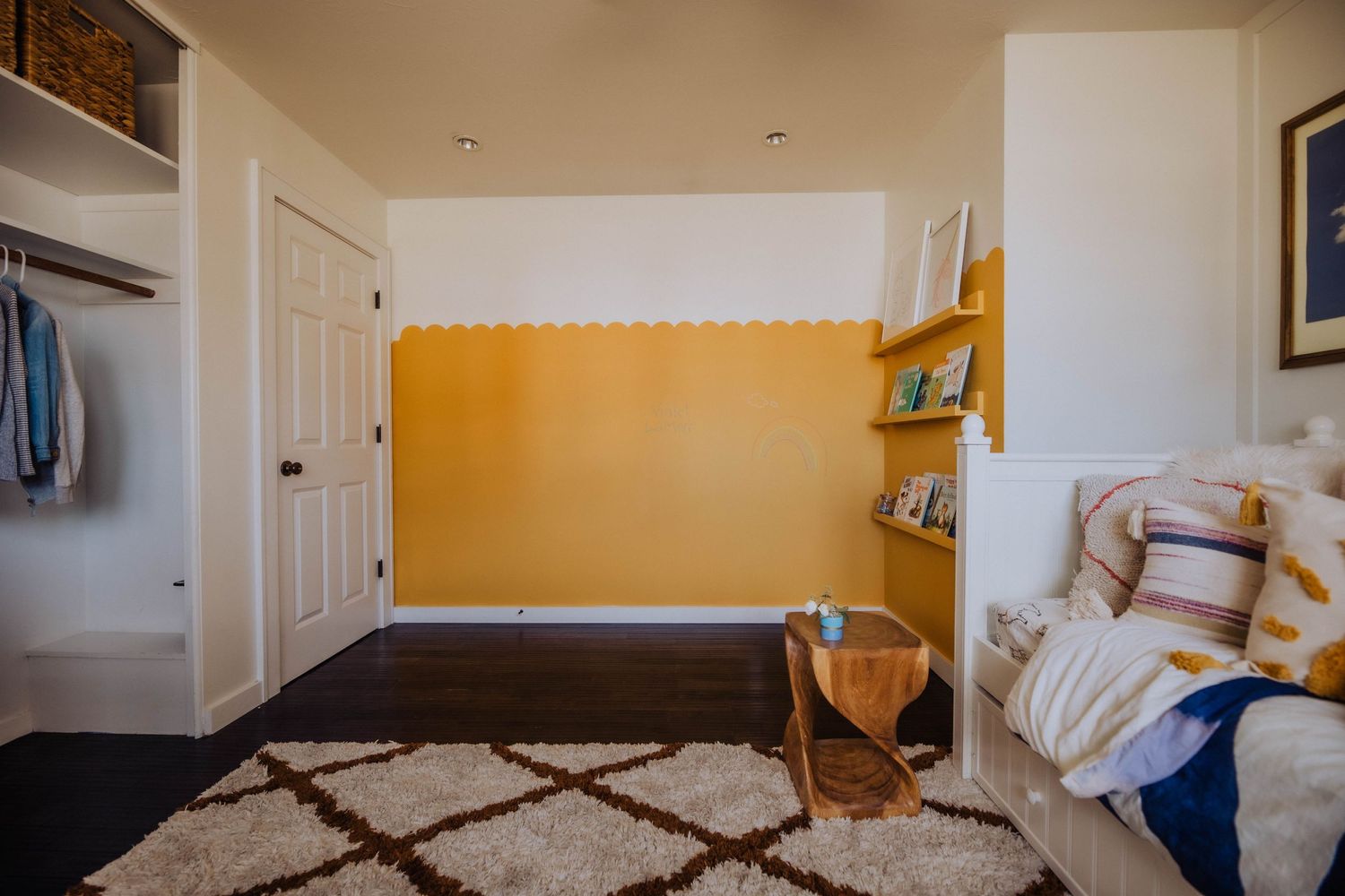 A cozy nursery room with white walls, a dresser, and decorative wall art featuring blue floral designs.