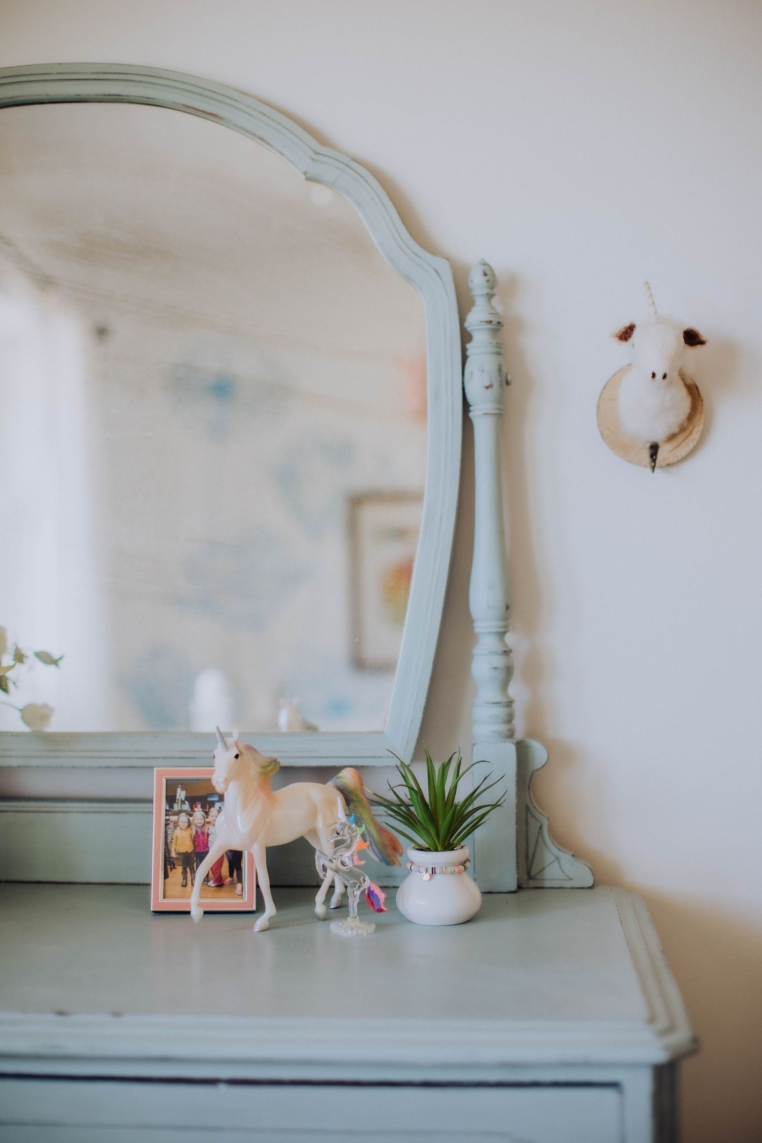Mint green vintage dresser with decorative items and a small mirror.