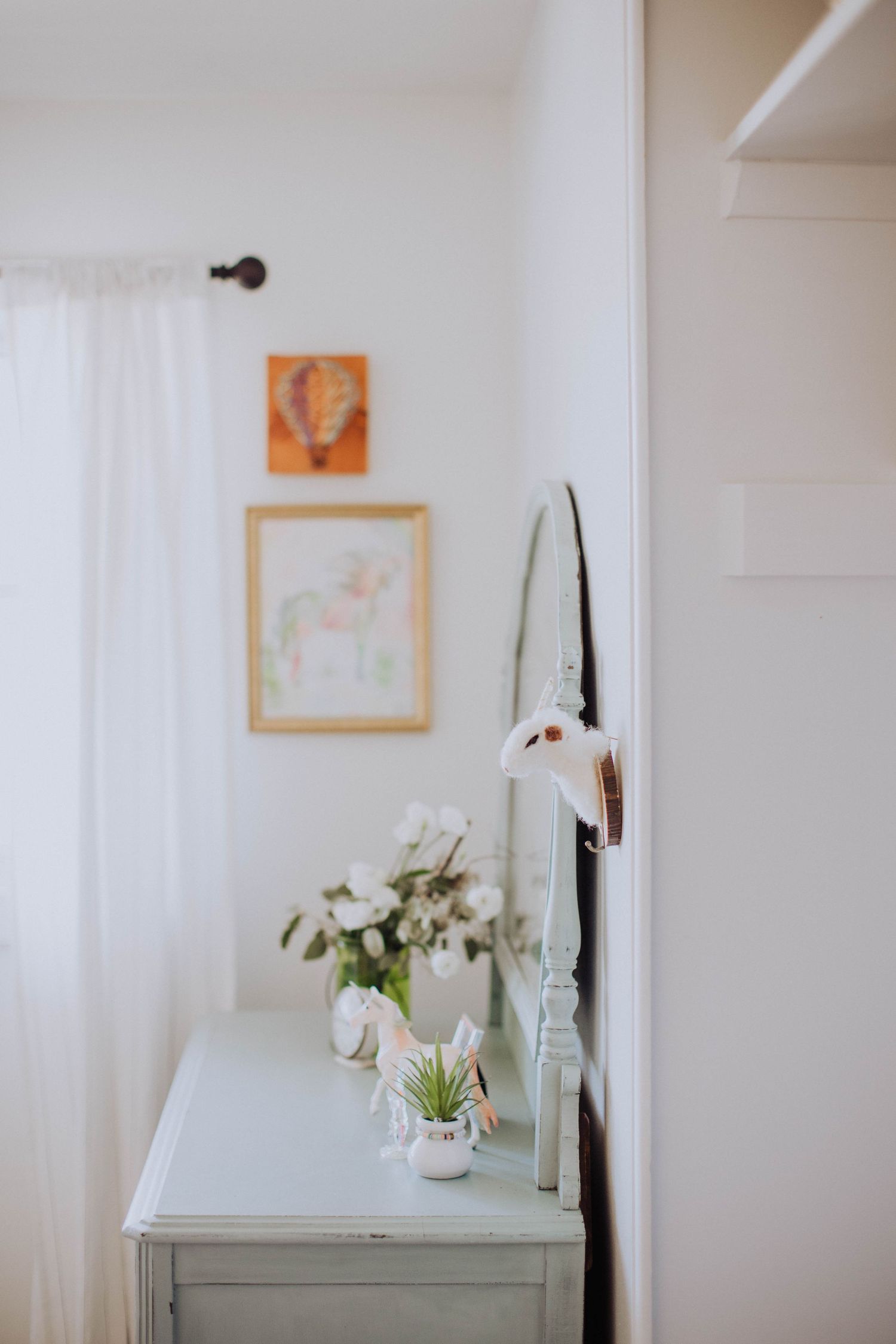 Minimalist bedroom corner with mint green furniture and framed artwork.