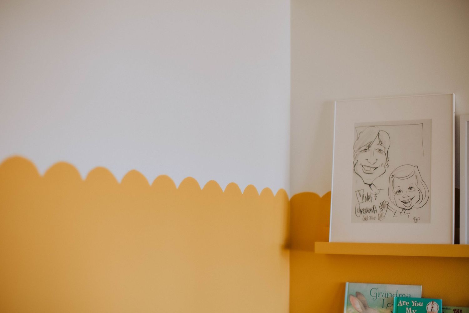 Yellow wall with white trim and floating shelves displaying artwork.