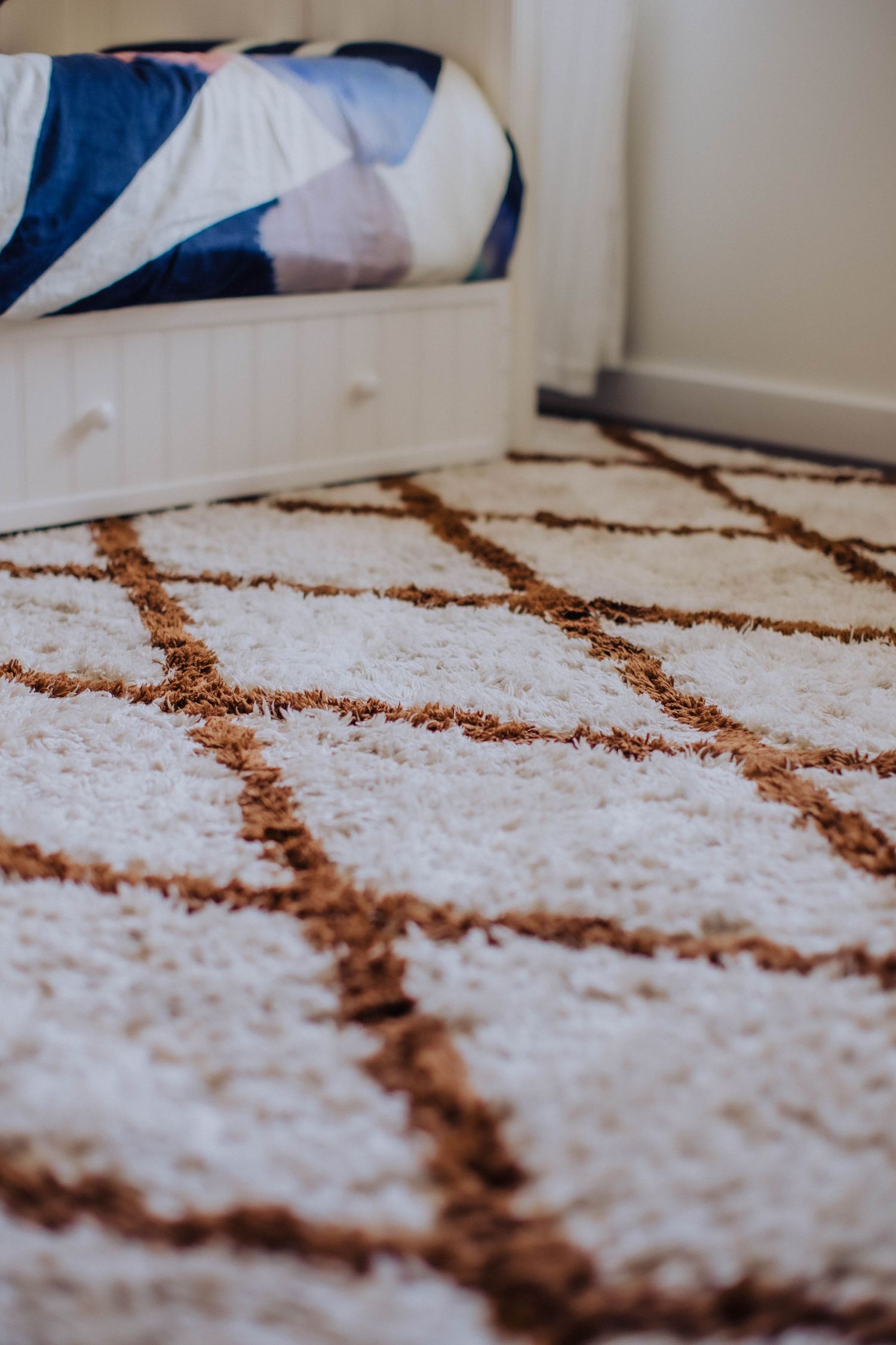 Close-up of a plush white carpet with geometric brown pattern.