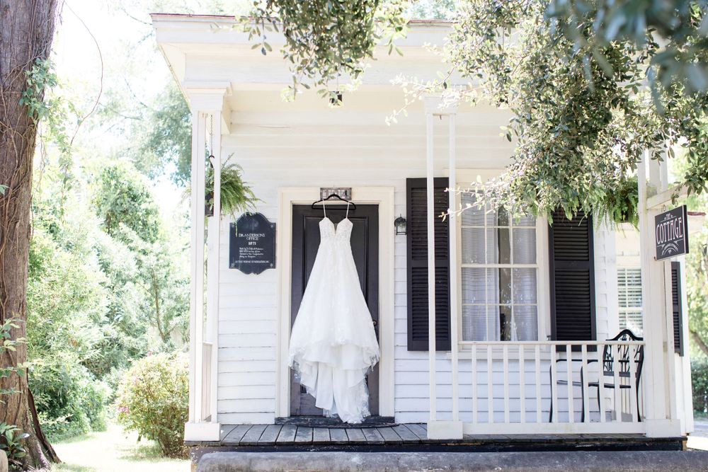 Wedding gown hanging on white southern style house with black shutters and porch.