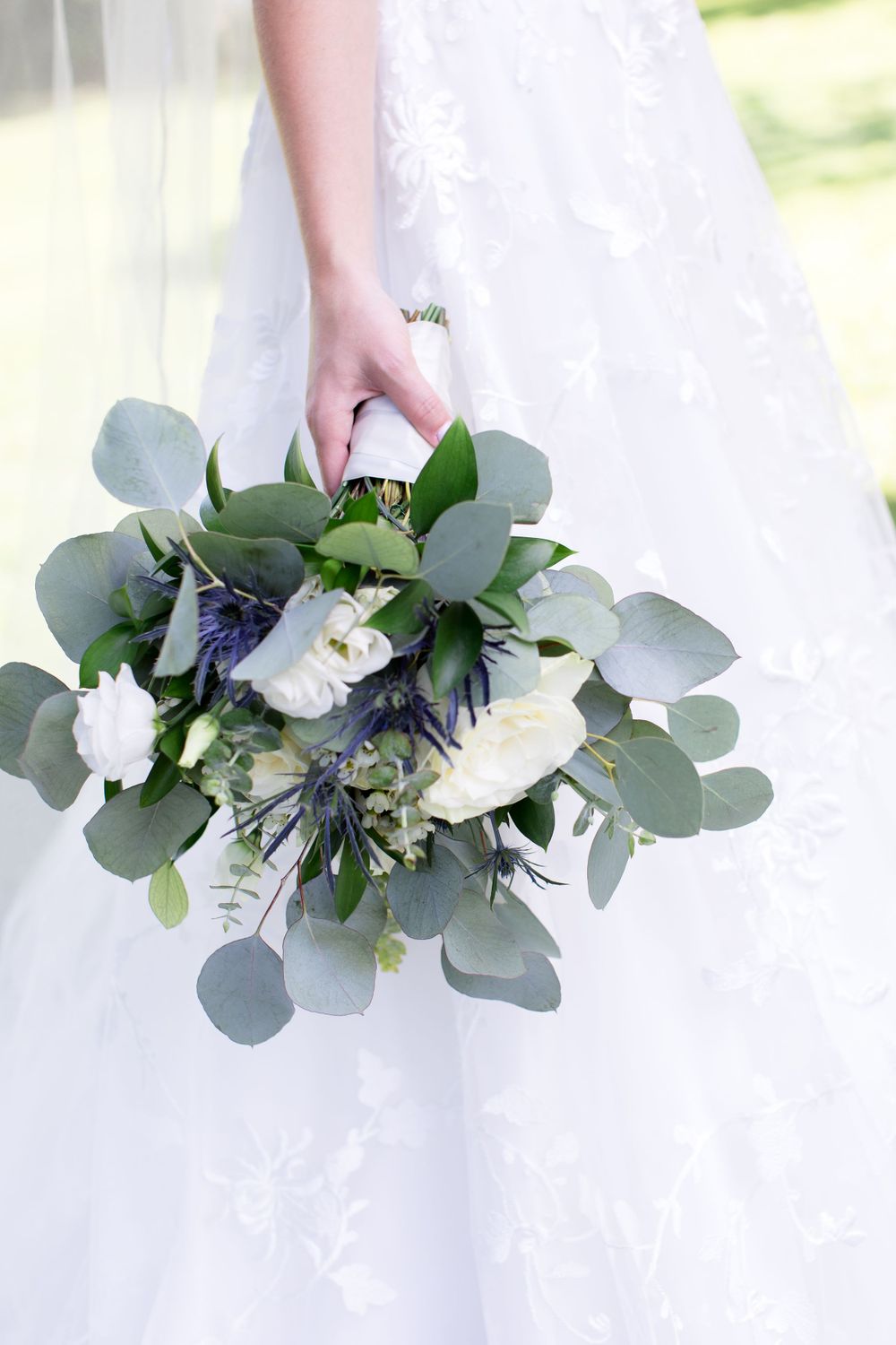 Elegant white and green bridal bouquet with eucalyptus leaves and white flowers.