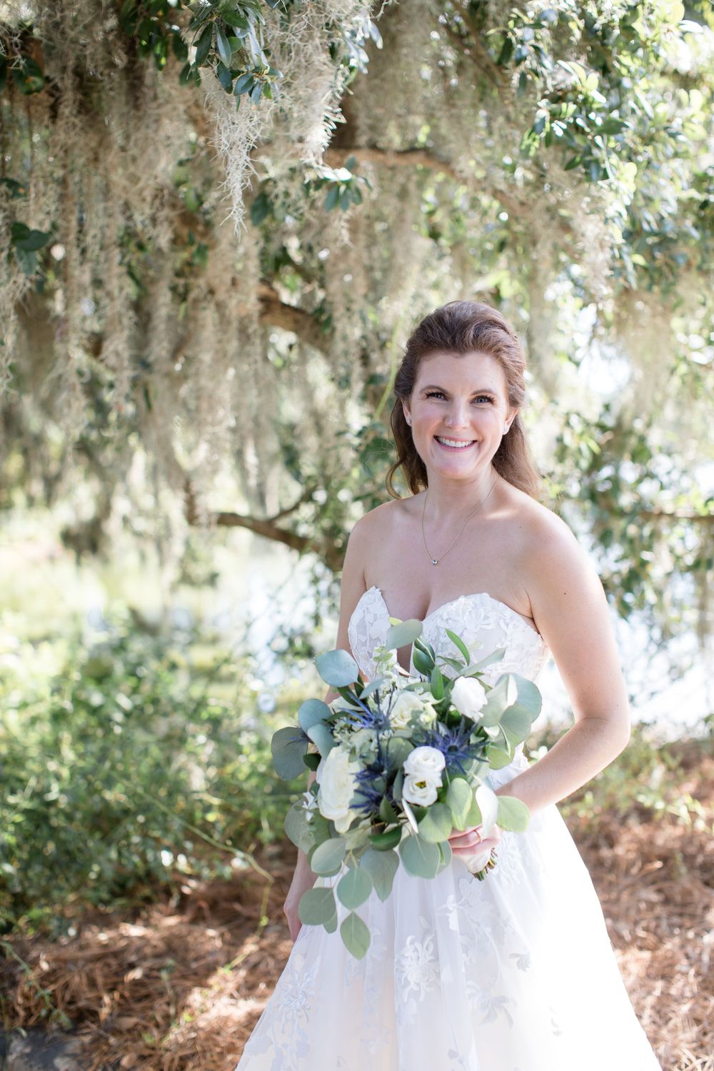 Bridal portrait under Spanish moss with white and green bouquet.