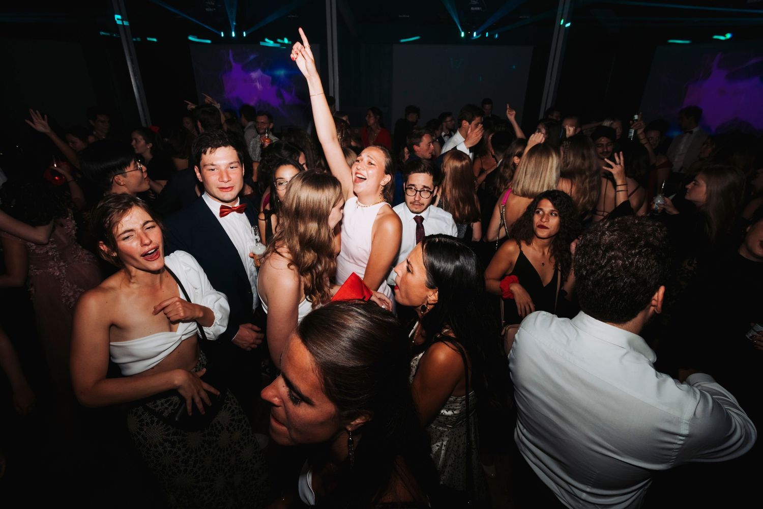 Energetic crowd dancing and celebrating at a formal evening wedding reception.