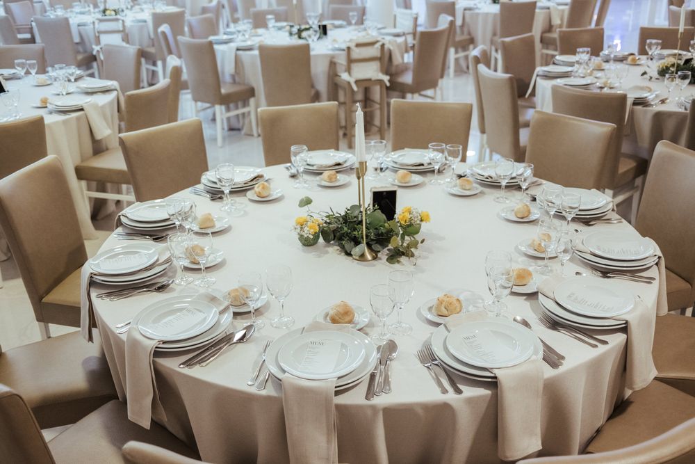 Mesa redonda para banquete, posta com toalhas de mesa brancas e individuais para uma receção elegante.