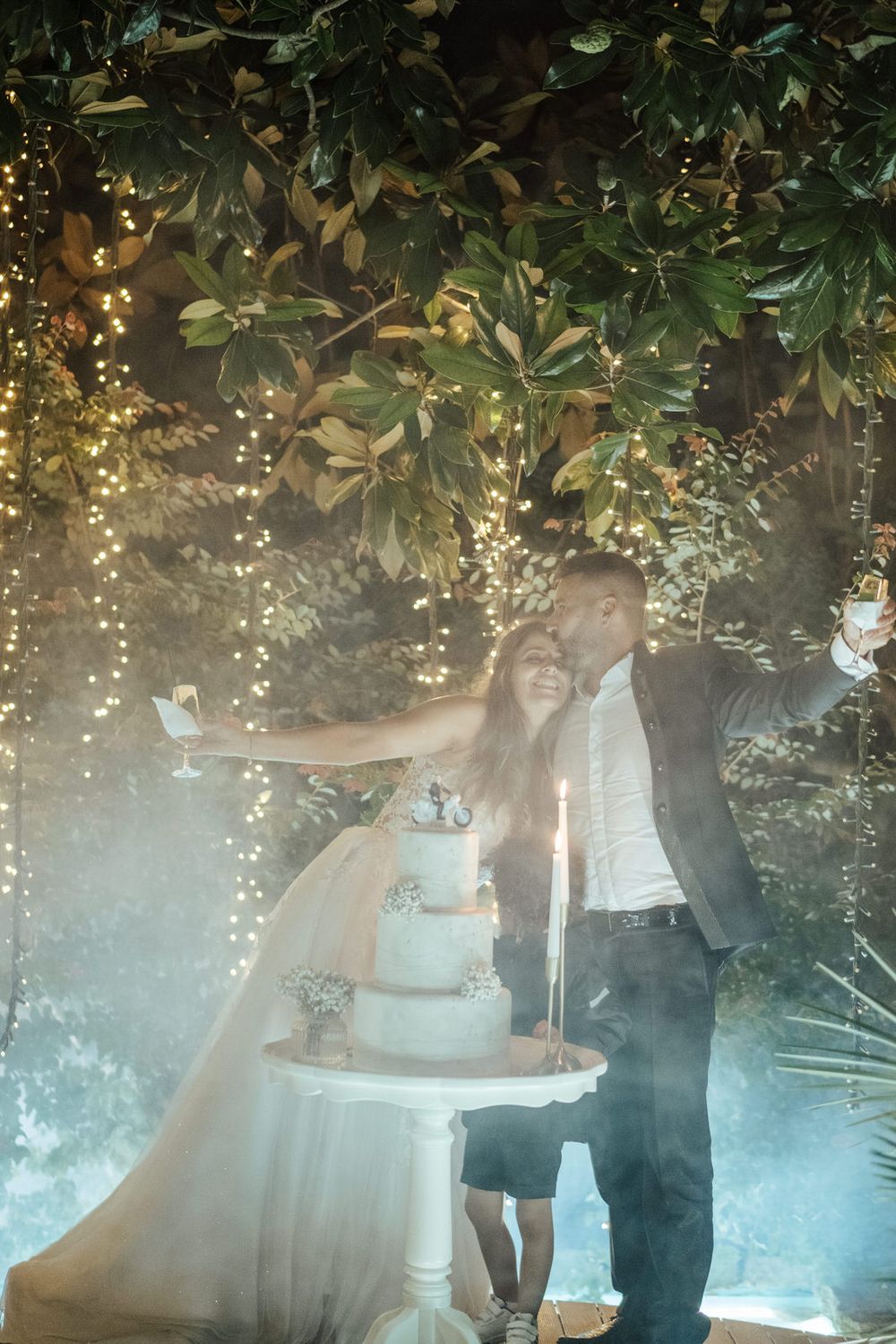 Cena de casamento etérea com luzes de fadas cintilantes e vegetação criando uma atmosfera mágica.
