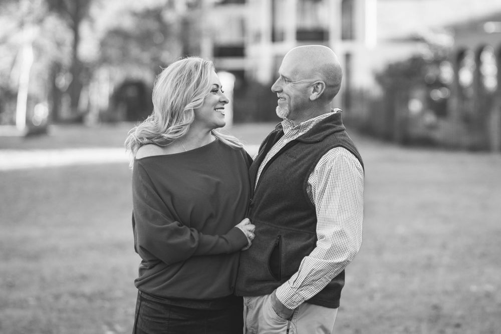 A black and white portrait of a couple sharing an intimate moment outdoors.