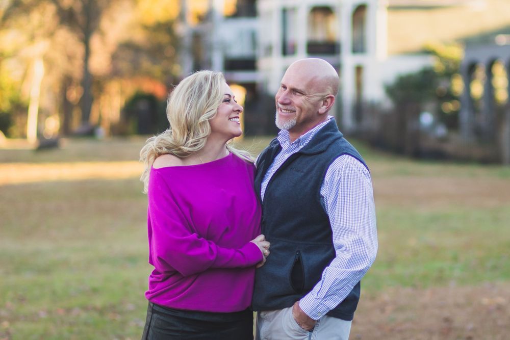 A couple shares a joyful moment together outdoors in autumn, wearing coordinated casual attire.