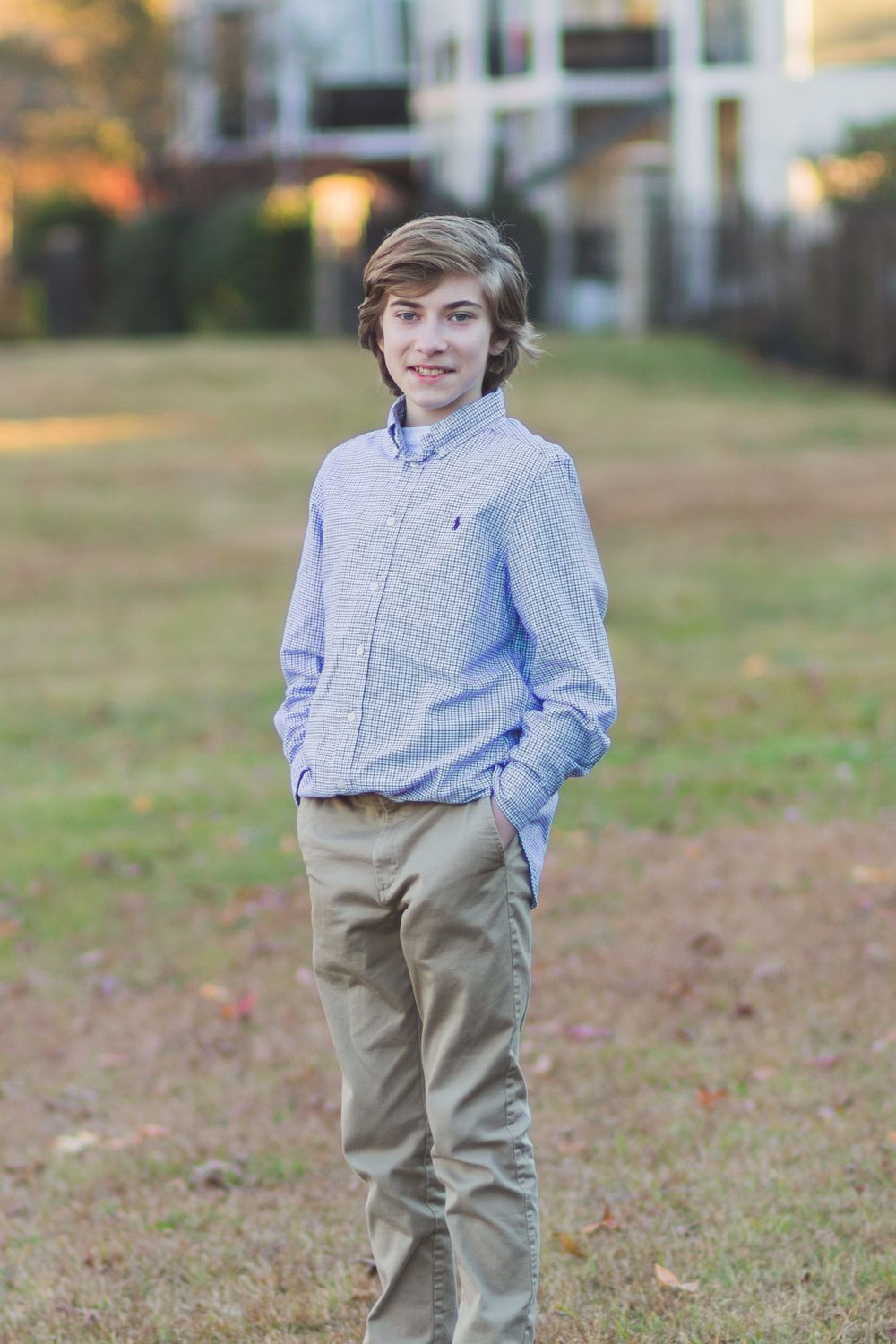 Young person in business casual attire stands outdoors in front of an apartment building.