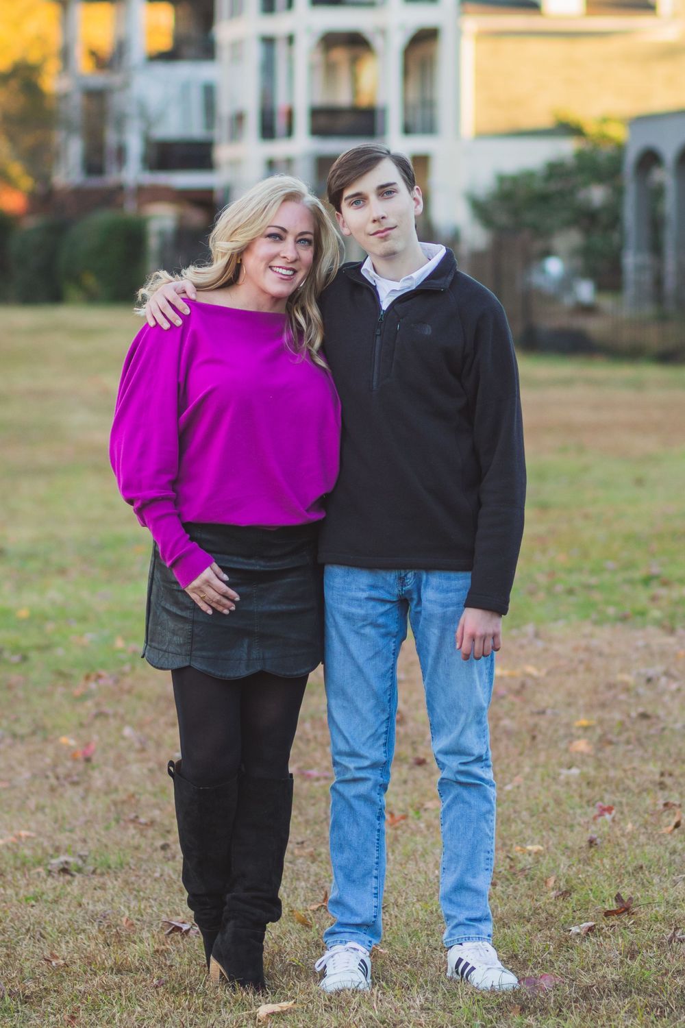 Mother and son pose together outdoors, coordinating in magenta and black clothing.