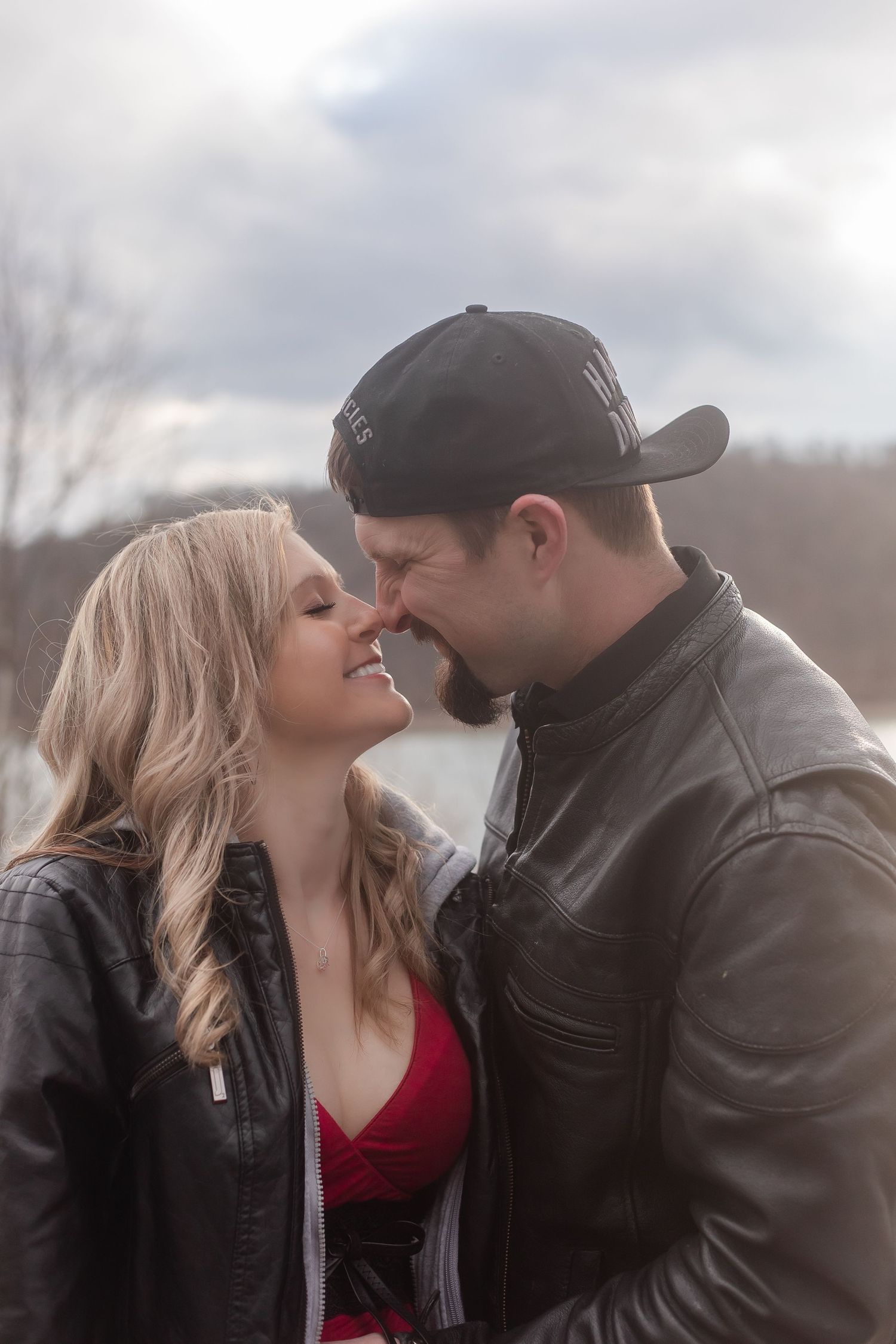 A couple shares romantic moments during their lakeside photoshoot wearing red and black.