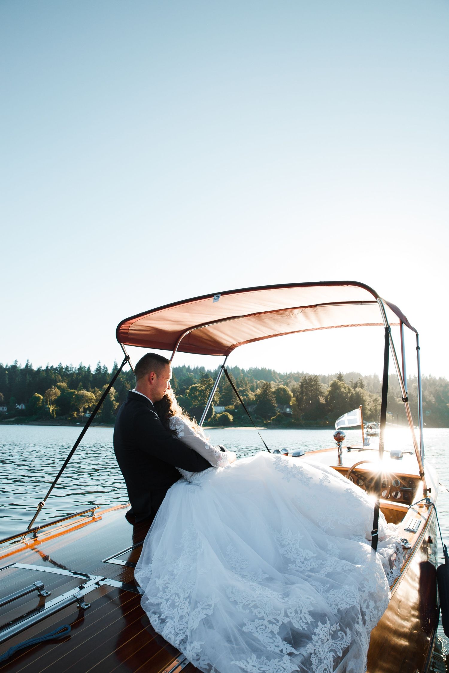 Bride and Groom hugging and sitting on a boat during sunset at an open lake