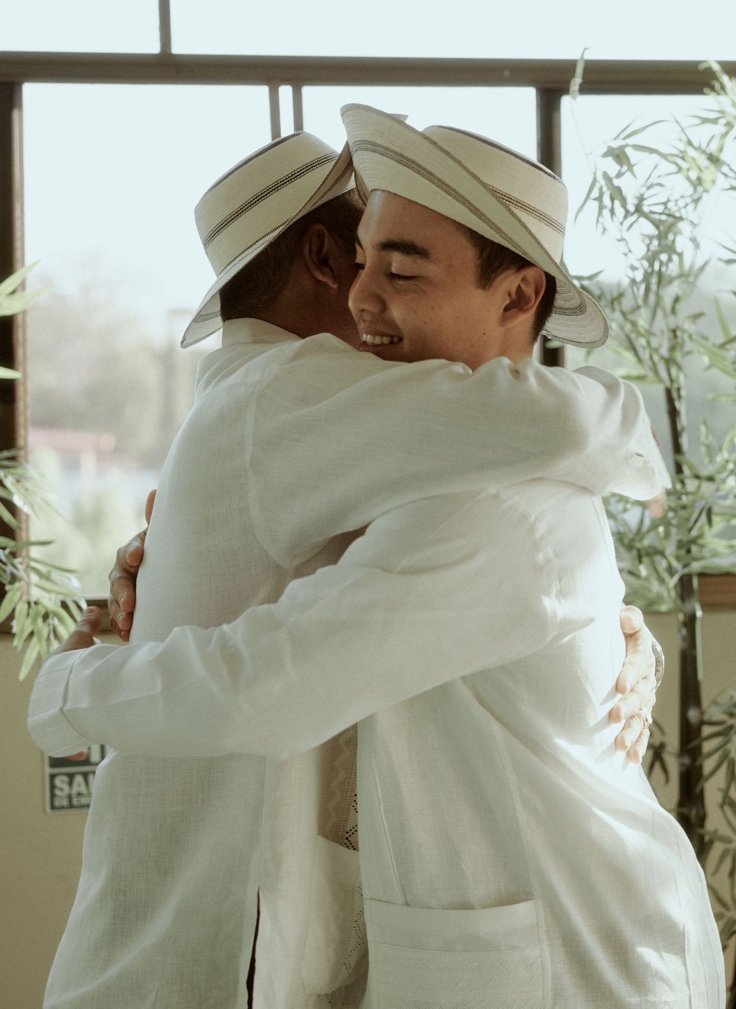 Two people in white attire sharing warm embrace during wedding celebration.