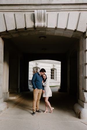 A couple embraces under an archway passage on a bright day.