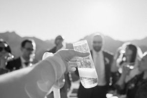 Guests raise champagne glasses for a toast with mountains in the background.