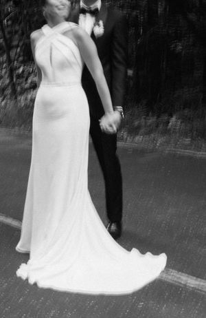Black and white photo of a bride and groom holding hands, showcasing her flowing white dress.