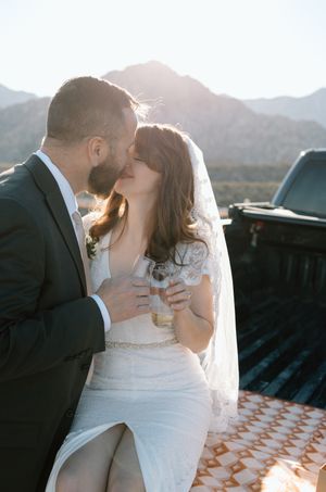 A couple shares an intimate moment against a mountain backdrop at sunset.
